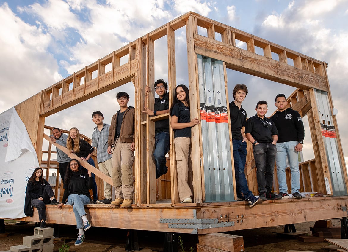 Cooper Proulx (third from right) and team members stand within the eco-house they built from the ground up. 