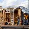 UC Riverside mechanical engineering undergrads work to cover a section of an exhibition model of an energy-efficient home on Wednesday, January 10 2024, in an empty lot next to the SRC.  (UCR/Stan Lim)