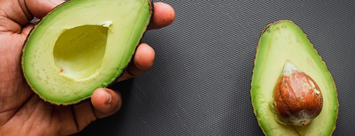 a hand holding an open avocado