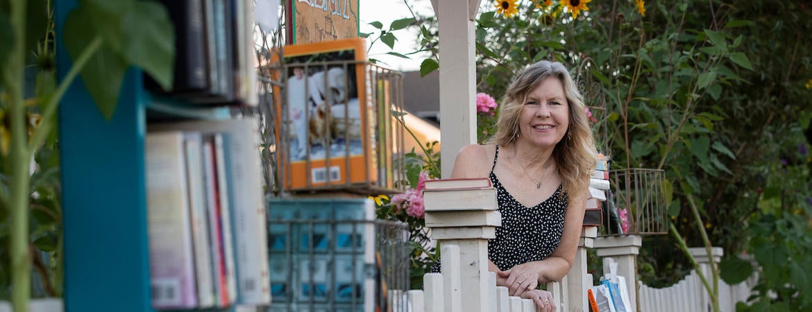 Author Susan Straight leans on her fence next to her fence library.