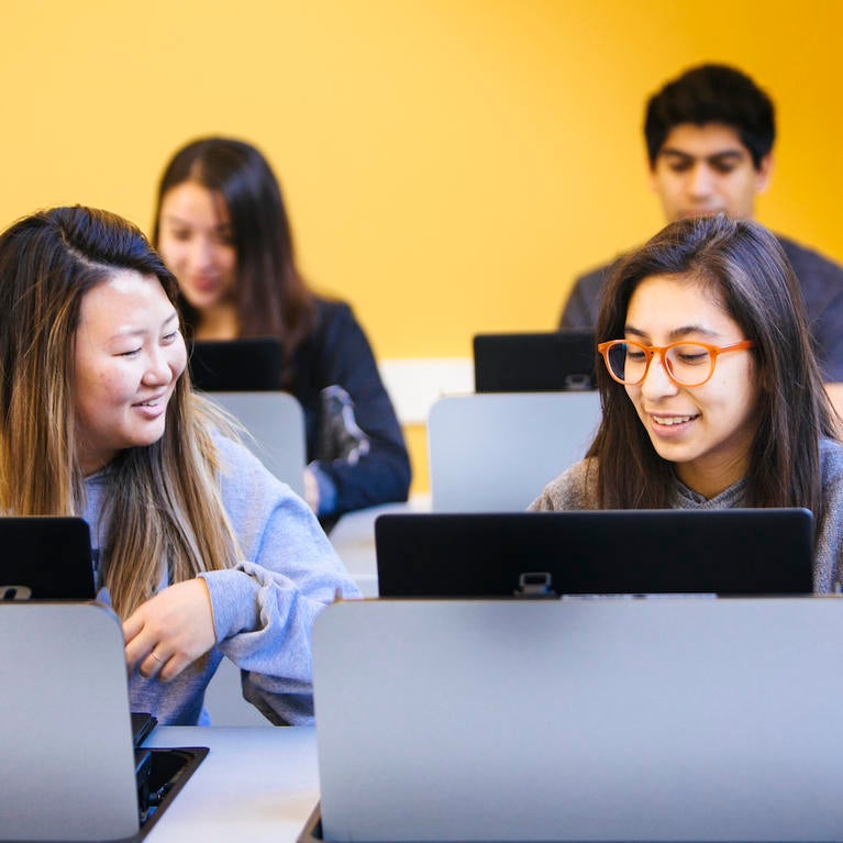 UCR students look at computers in a classroom