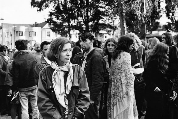 Writer Joan Didion walks among hippies during a gathering in Golden Gate Park, San Francisco