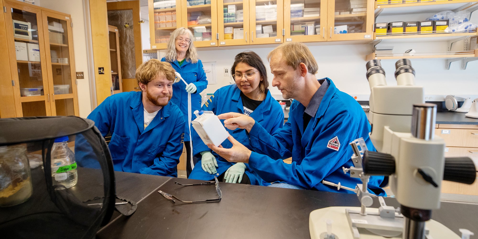 Boris and Barbara watch bees feed in a holder with apiary manager Owen Wagner (left) and lab assistant Brenda Garate-Galindo (center) in their lab.