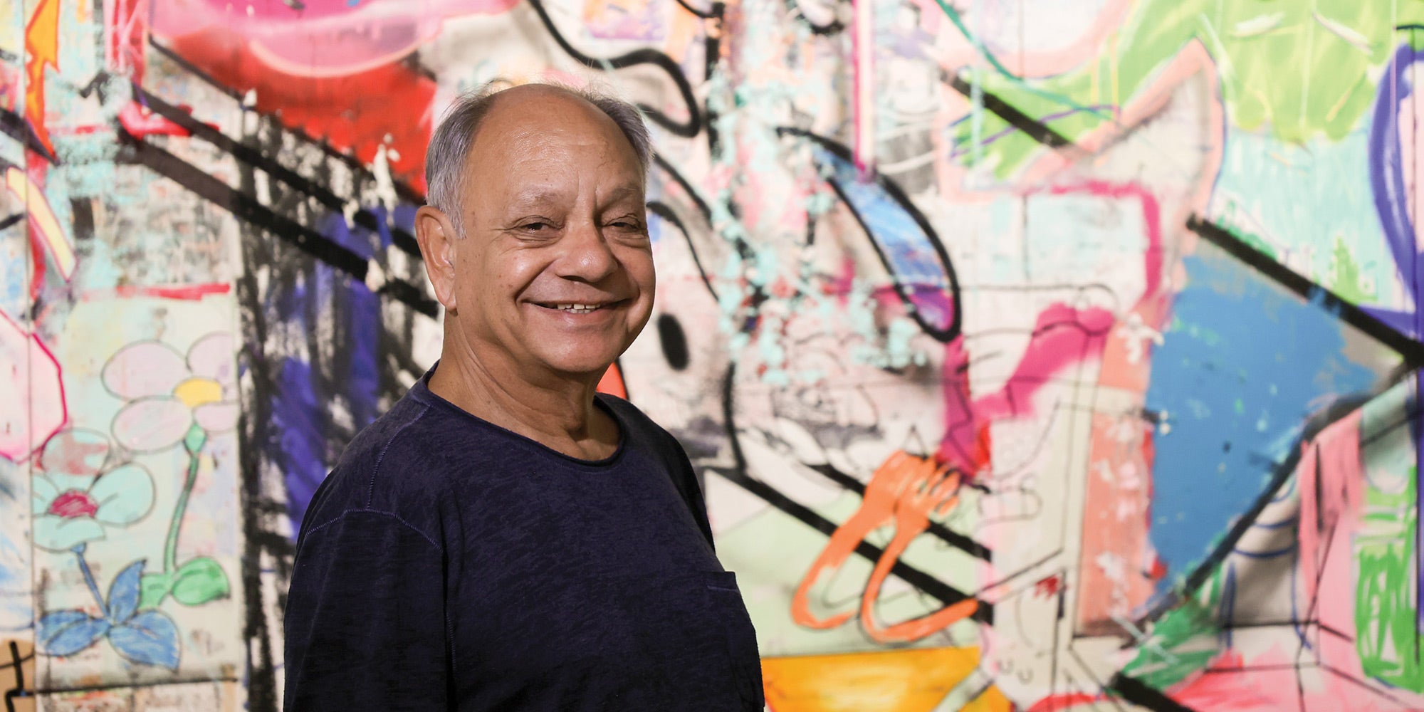 Cheech Marin in front of artwork by Cande Aguilar