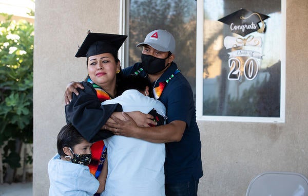 Jacqueline Hernandez Rico, 33, gets a hug from her sons Eric Salvador Hernandez, 11, Ivan Santiago Hernandez, 6, and husband Irvyn Hernandez while watching the virtual Raza Grad ceremony on June 13, 2020 in Perris. (UCR/Stan Lim)