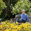 Lewis sits on a bench surrounded by flowers and trees at the Huntington.
