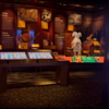 A photo showing items on display at the exhibition and eight-foot-tall touch-screen monitors with interactive displays.