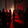 The production crew navigates backstage under red light during the final dress rehearsal.