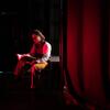 Cast member Zirei Chu thumbs through a prop book while waiting for the final dress rehearsal to start.