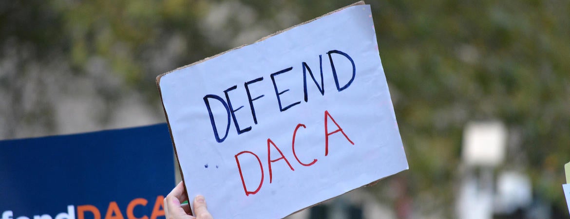 Supporters hold up a "defend DACA" poster at a rally