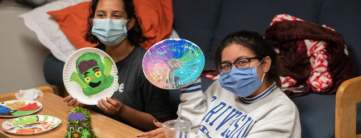 Marjorie Serrano, 18, left, and Miezue Primo, 18, show off their pain night creations as they interact with their resident advisor, Thomas Valenzuela, through Zoom at Pentland Hills Residence Hall on October 12, 2020. (UCR/Stan Lim)