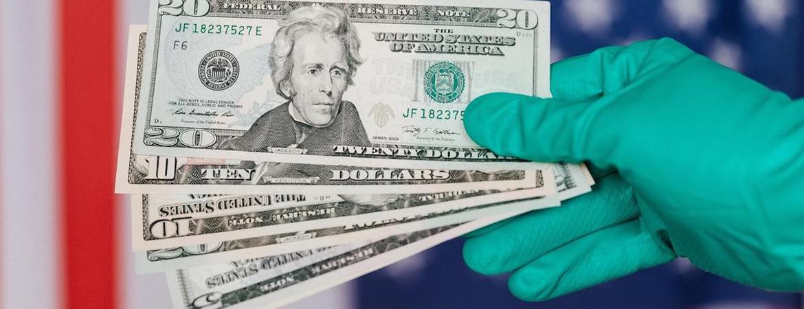 A gloved hand holds multiple $20 bills