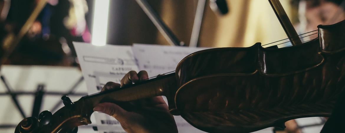 Person playing violin with sheet music on stand