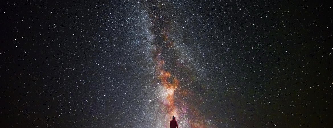 A man on a mountain looks at the stars.