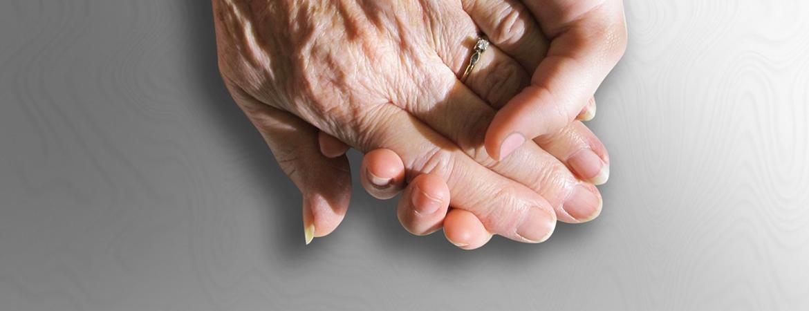 The hand of an old person holding the hand of a younger person