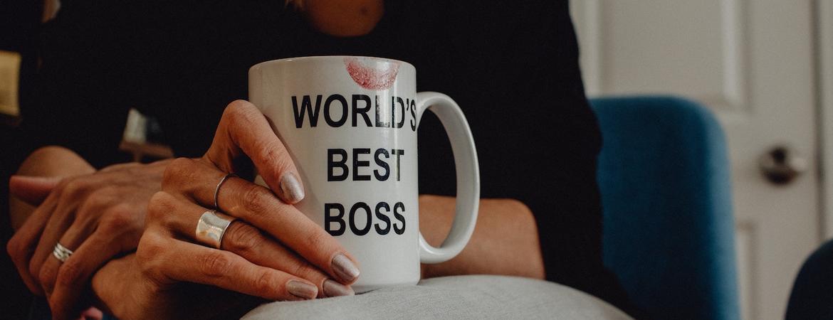 A woman holding a mug that says World's Best Boss