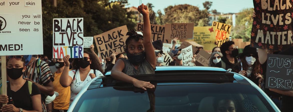 A girl raises her fist from the roof of a car at a Black Lives Matter protest