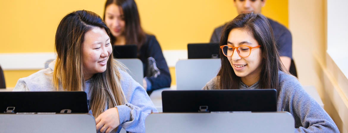 UCR students look at computers in a classroom