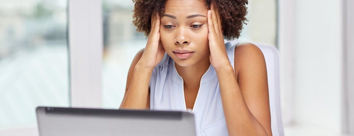 A stressed out woman sits in front of a laptop