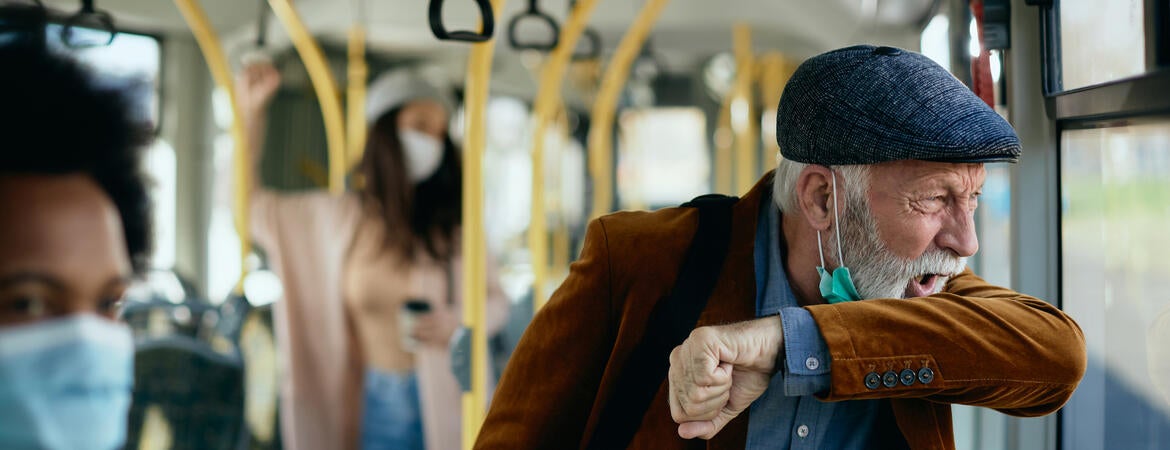 Stock image of a man coughing on a bus.