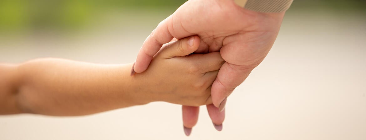 Woman holds hand of child