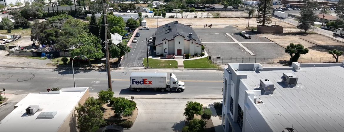 Built in 1928, St. Mark’s Missionary Baptist Church is now surrounded by warehouses. (Aerial footage of Valley Truck Farms by Tamara Cedré and Adrian Metoyer III, 2024, courtesy of the artists and A People’s History of the I.E.)