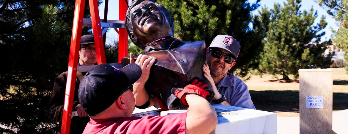 Workers remove a bust of Cesar Chavez from its pedestal.
