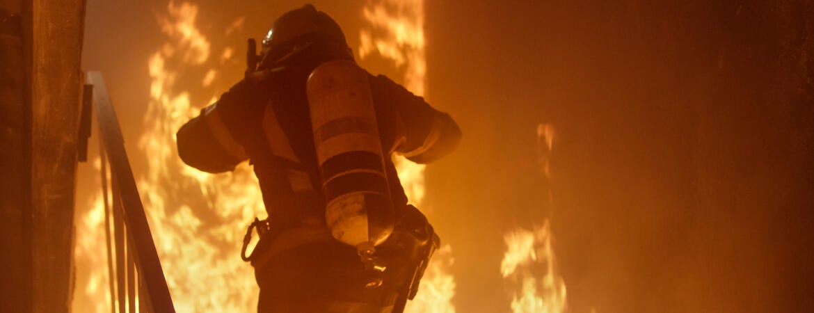 Photo shows a firefighter entering a burning building.