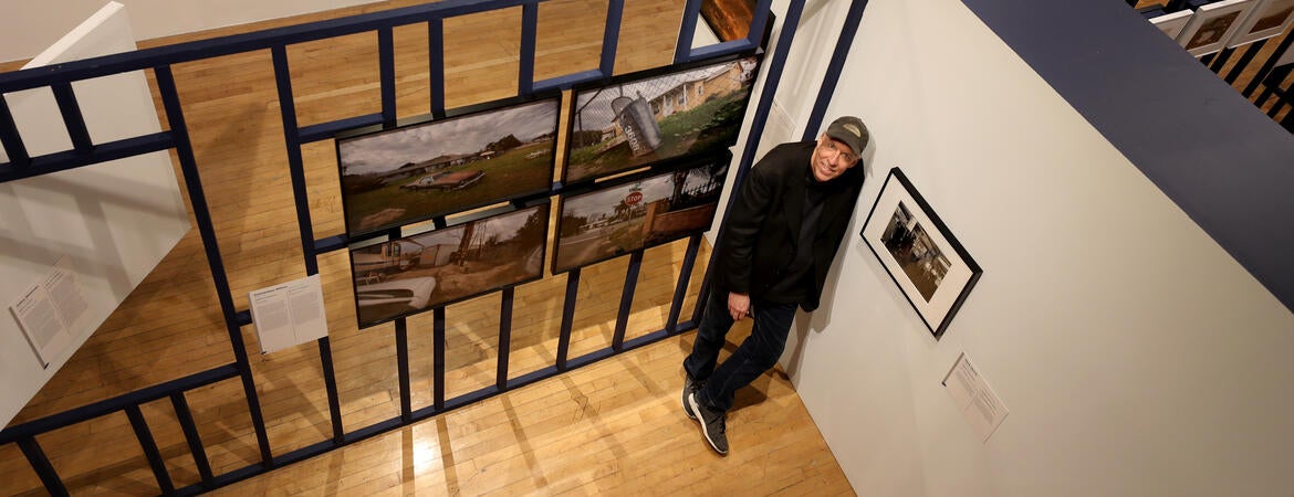 Douglas McCulloh posing with photographs at a UCR ARTS exhibition