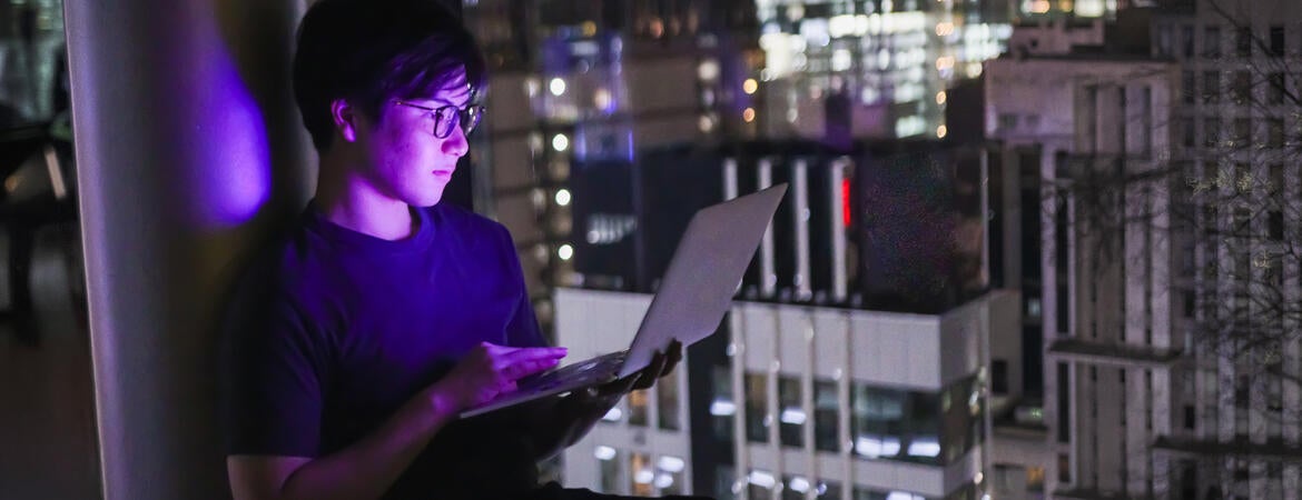 Young man with laptop overlooking a city