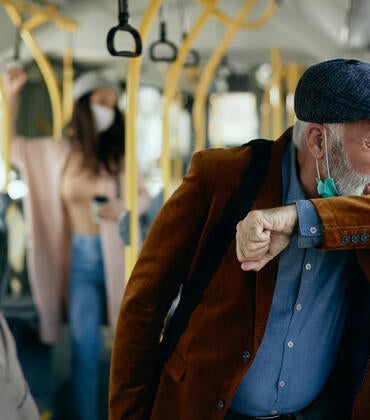 Stock image of a man coughing on a bus.