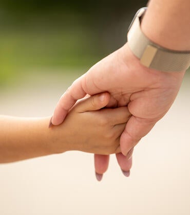 Woman holds hand of child