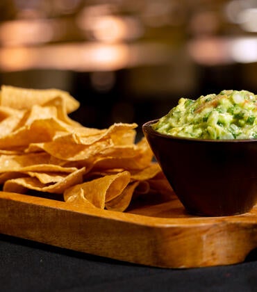 tortilla chips and guacamole served on a wooden tray