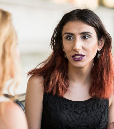 Transgender woman talking with a person whose back is to the camera.