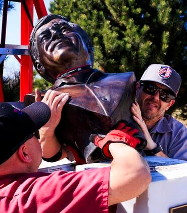Workers remove a bust of Cesar Chavez from its pedestal.