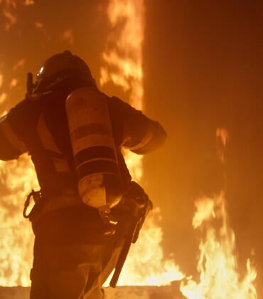 Photo shows a firefighter entering a burning building.