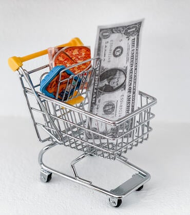 Shopping cart with a dollar and frozen pizza