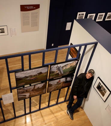 Douglas McCulloh posing with photographs at a UCR ARTS exhibition