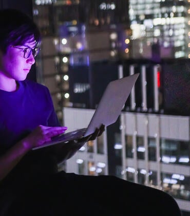 Young man with laptop overlooking a city