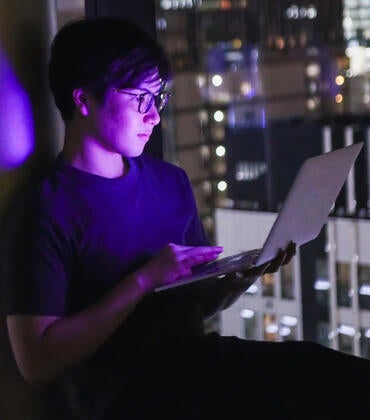 Young man with laptop overlooking a city