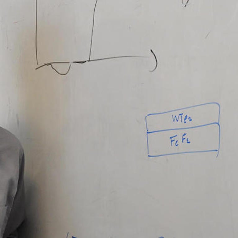 Researcher Jing Shi stands in front of white board