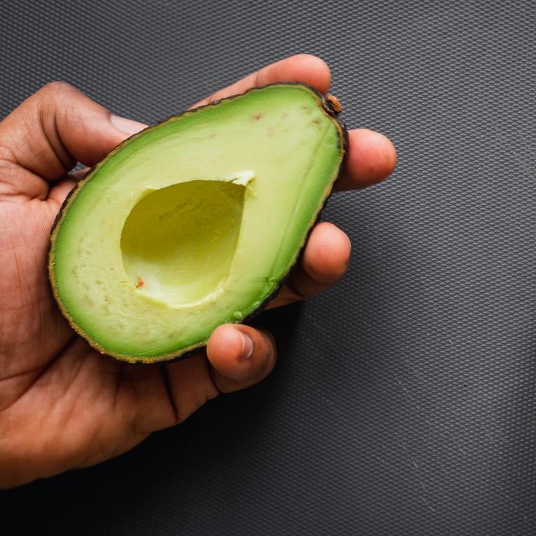 a hand holding an open avocado