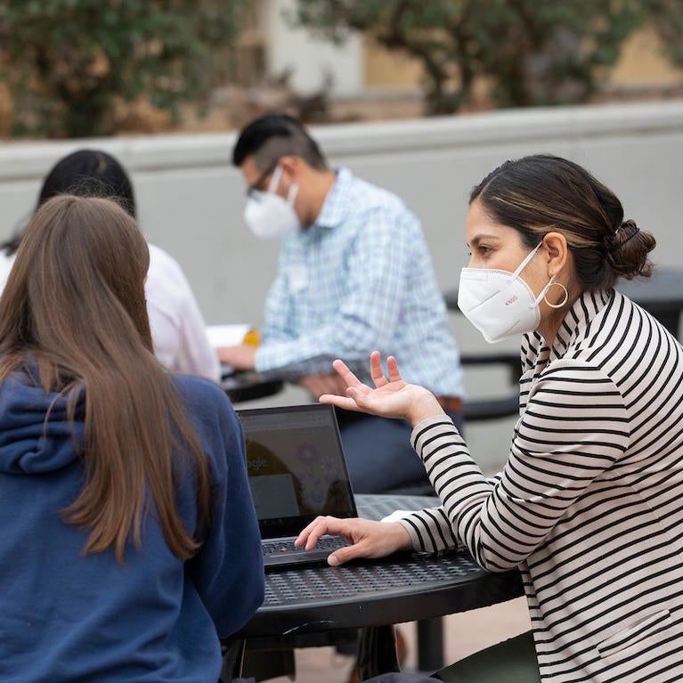 Liliana Castro, high school advisor, front, and Hector Navarette, assistant director, both with UCR’s Educational Talent Search, meet with students about applying to colleges on Thursday, October 7, 2021, at Arroyo Valley High School in San Bernardino. (UCR/Stan Lim)