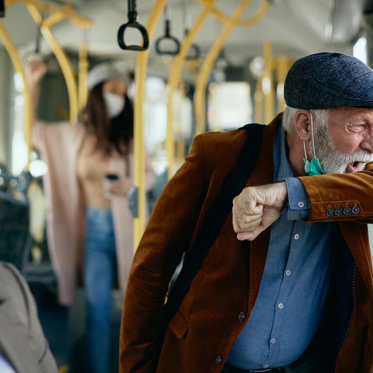 Stock image of a man coughing on a bus.