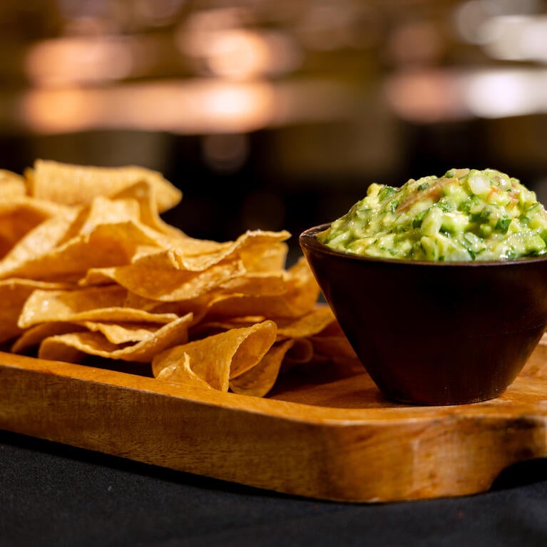 tortilla chips and guacamole served on a wooden tray