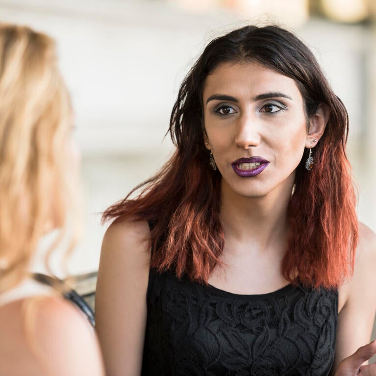 Transgender woman talking with a person whose back is to the camera.