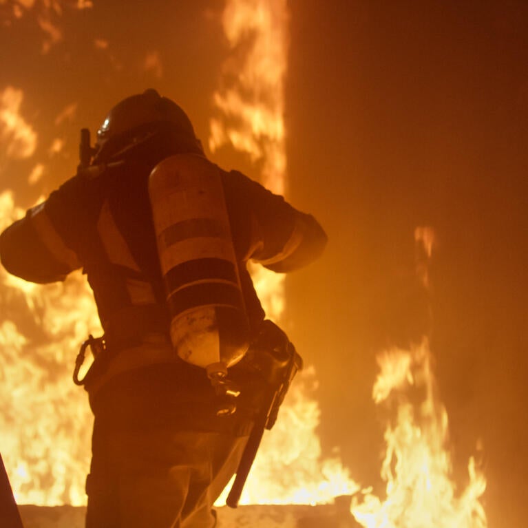 Photo shows a firefighter entering a burning building.