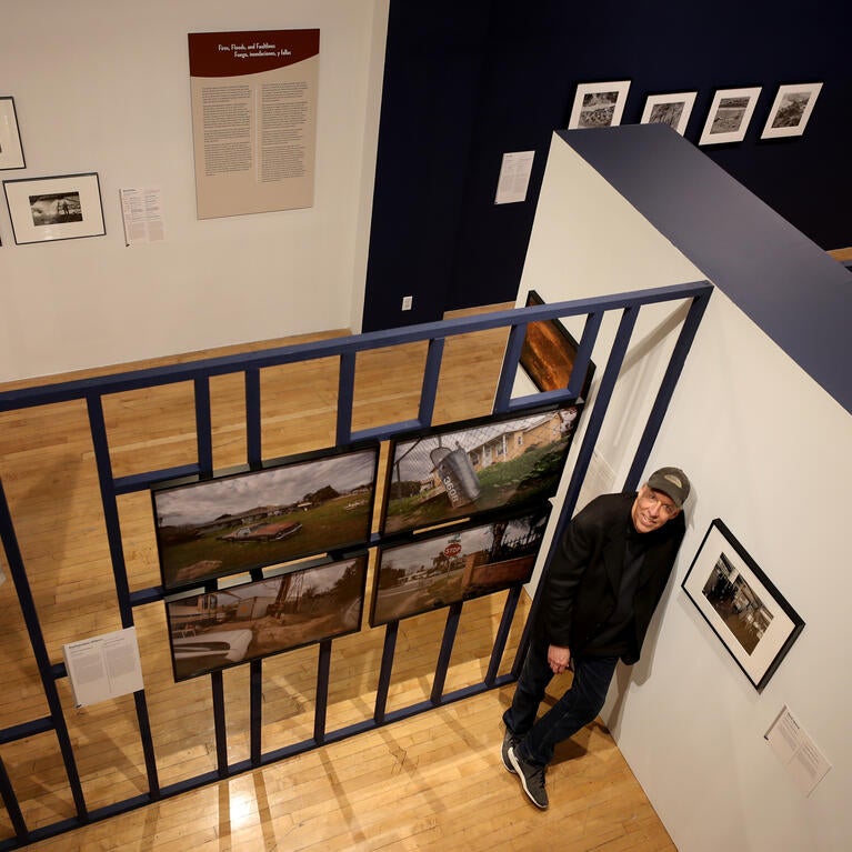 Douglas McCulloh posing with photographs at a UCR ARTS exhibition