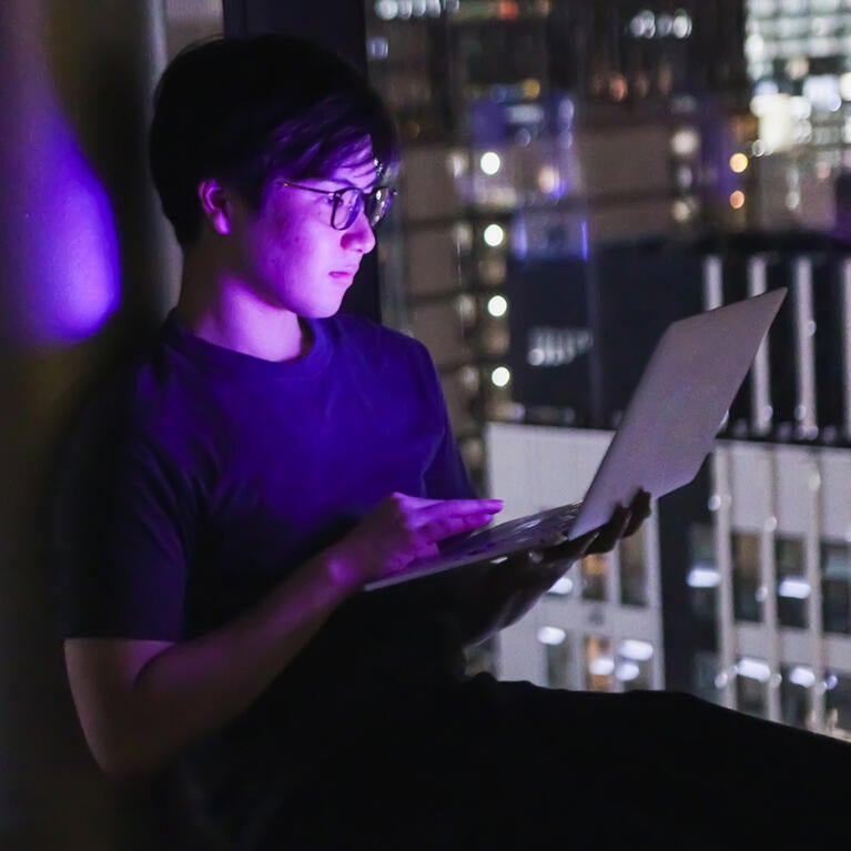 Young man with laptop overlooking a city