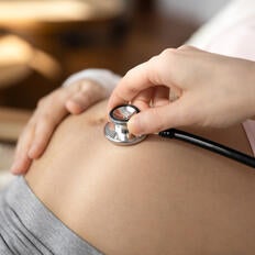Close up of doctor listen to baby bump